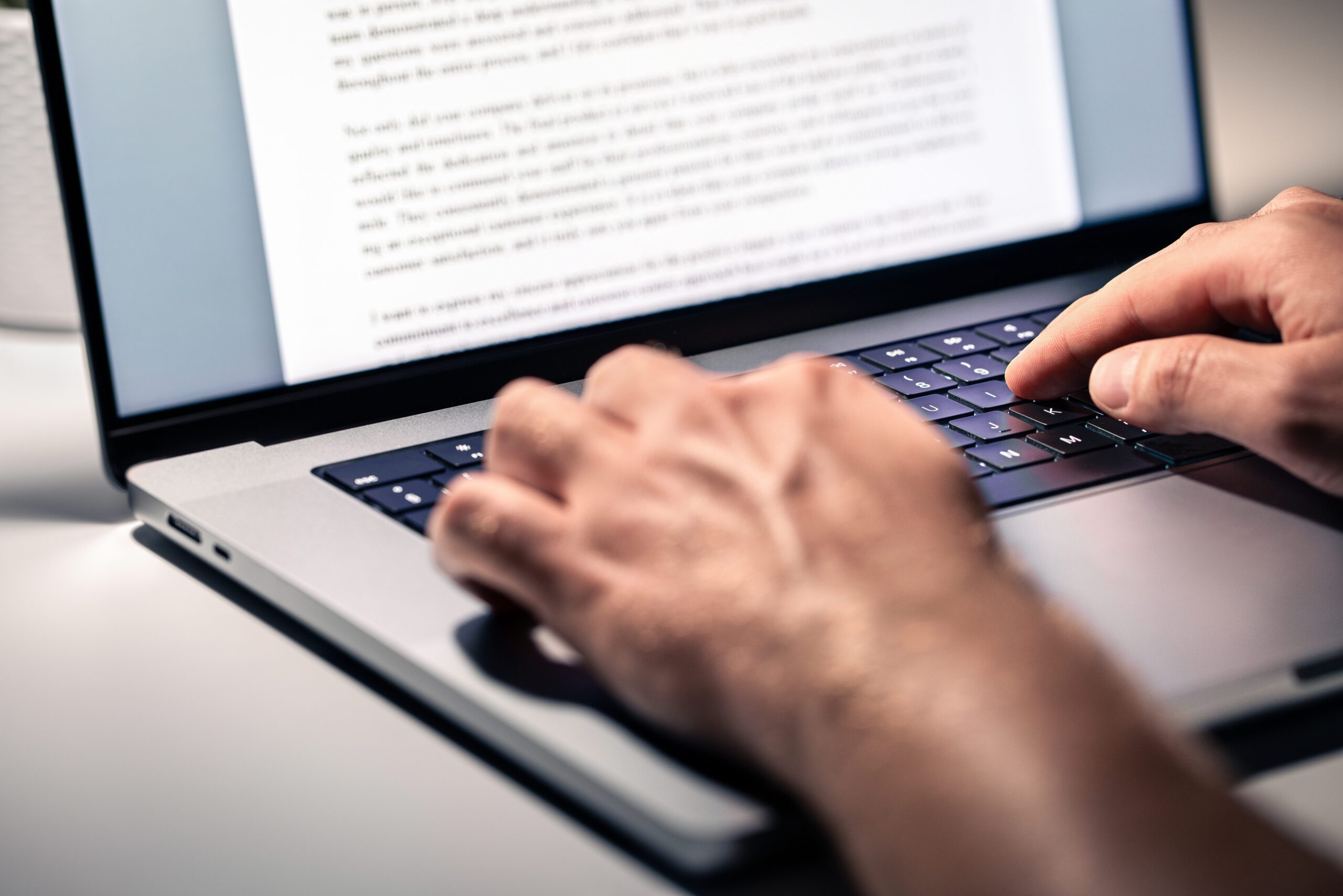 An image of hands typing on a laptop keyboard, writing content.